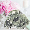 Mineral specimen on a stand with pink flowers in the background